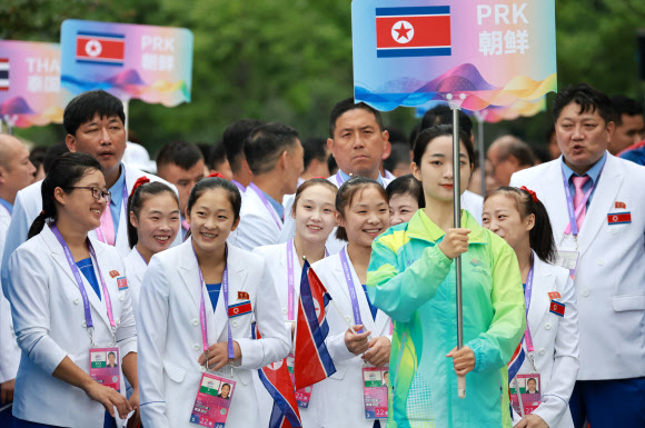 2022 항저우 아시안게임(AG) 개막을 하루 앞둔 22일 중국 항저우시 아시안게임 선수촌 국기광장에서 열린 공식 입촌식에서 안창옥(왼쪽 세 번째), 김손향(왼쪽 다섯 번째) 등 북한 기계체조 선수단이 입장을 기다리며 대화하던 중 미소짓고 있다. 2023.9.22 연합뉴스