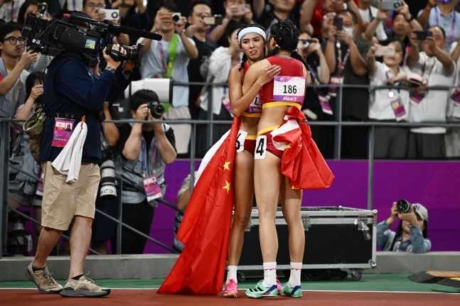 항저우 아시안게임 육상 경기에서 각각 6번과 4번 트랙에서 달려 ‘6’, ‘4’ 스티커를 붙히고 있는 중국 선수 린위웨이(왼쪽)와 우옌니가 서로 포옹하고 있다. 로이터 뉴스1