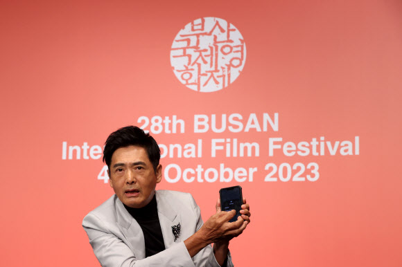 홍콩 배우 저우룬파(주윤발)이 5일 오후 부산 해운대구 KNN시어터에서 제28회 부산국제영화제 올해의 아시아영화인상 기자회견에서 개인 휴대전화로 찍은 사진을 참석자들에게 전달하고 있다. 2023.10.5 연합뉴스