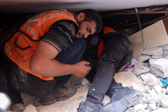 팔레스타인 시민의용대 팀원들이 9일(현지시간) 가자지구의 라파 시에서 이스라엘 공습에 무너진 건물 잔해 속에서 생존자나 희생자를 찾고 있다. 라파 AFP 연합뉴스