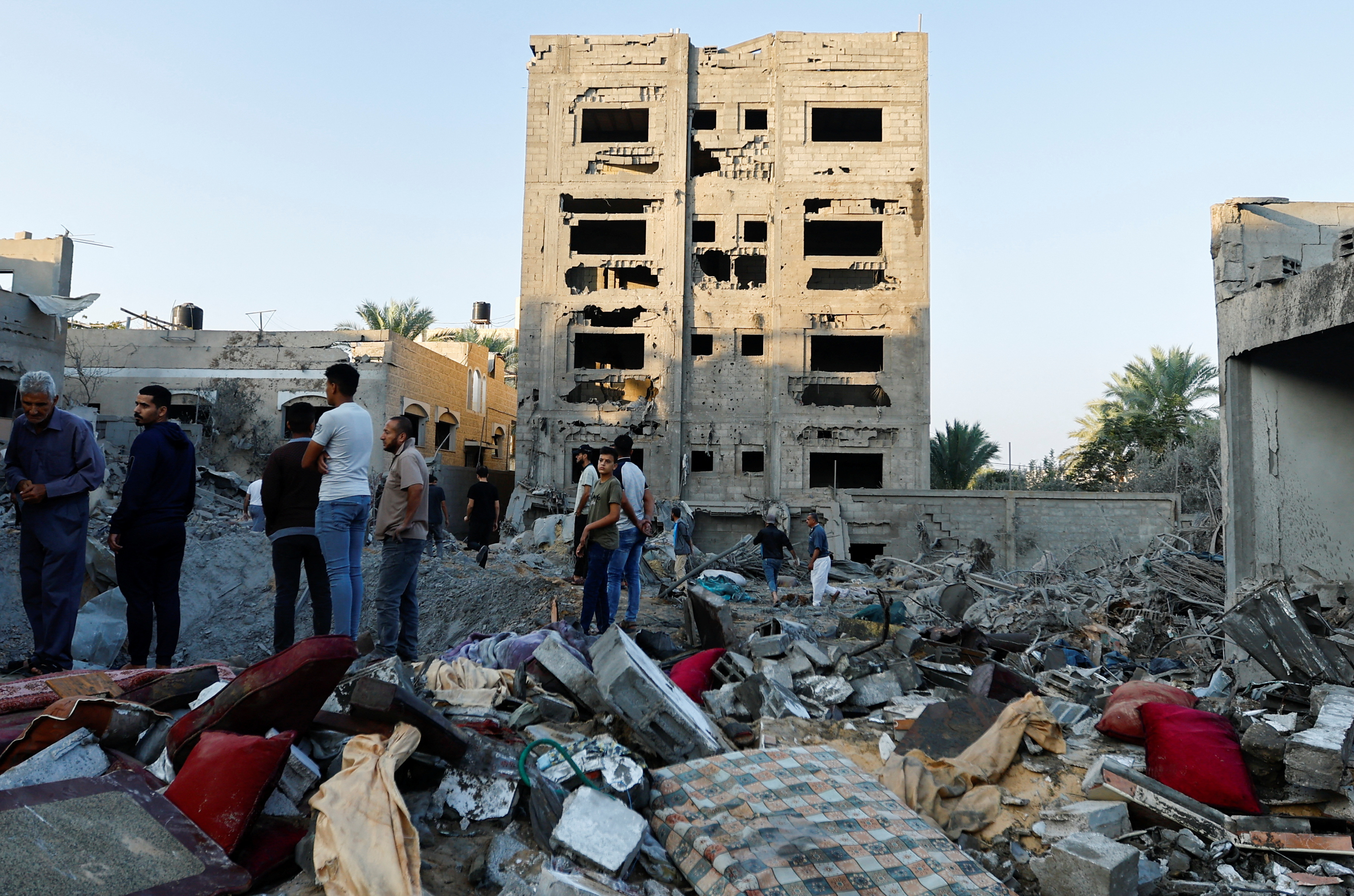 팔레스타인인들이 12일(현지시간) 가자지구 남부 칸 유니스에서 이스라엘과의 분쟁 중 공습으로 파괴된 건물을 바라보고 있다.  칸 유니스 로이터 연합뉴스