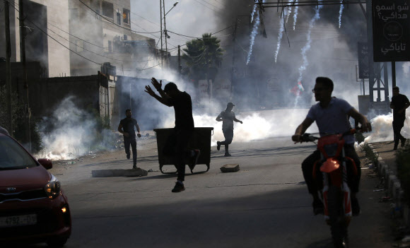 팔레스타인 요르단강 서안지구 나블루스 주민들이 13일(현지시간) 이스라엘 군이 최루탄을 쏘자 피해 달아나고 있다. 팔레스타인 자치정부 보건부에 따르면 이날 충돌로 최소 11명이 숨졌다. 나블루스 EPA 연합뉴스