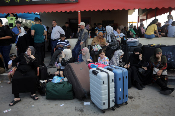 해외 여권을 소지한 사람들이 14일(현지시간) 이집트로 건너가는 유일한 생명줄인 라파 통로가 열리길 기다리고 있다. 이집트는 이중 국적자에 한해 국경을 개방한다고 밝혔지만 아직 통로는 열리지 않았다. 라파 UPI 연합뉴스