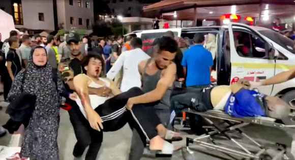 팔레스타인 가자지구의 가자시티에 있는 알아흘리 아랍 병원에 17일(현지시간) 폭탄이 명중돼 막대한 인명 피해가 발생한 직후 한 부상자가 다른 병원으로 급히 옮겨지고 있다. 로이터 TV 영상 캡처 로이터 연합뉴스