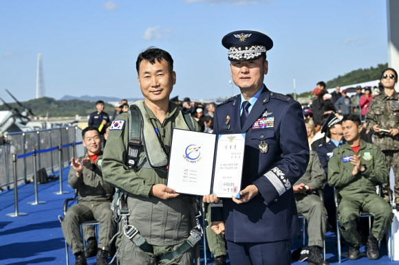 21일 경기도 성남 서울공항 ADEX 행사장에서 열린 제9기 국민조종사 및 명예조종사 임명식에서 김종섭 국민조종사가 정상화 공군 참모총장과 함께 임명장을 들고 기념촬영을 하고 있다.  김씨는 순직 조종사의 친형으로 조카들이 고인의 헌신을 기억할 수 있도록 국민조종사에 지원했다. 2023.10.21. 공군 제공