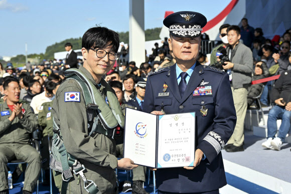 21일 경기도 성남 서울공항 ADEX 행사장에서 열린 제9기 국민조종사 및 명예조종사 임명식에서 뇌종양 환자를 수술치료하는 신경외과 의사인 김의현 국민조종사가 정상화 공군 참모총장과 함께 임명장을 들고 기념촬영을 하고 있다. 2023.10.21. 공군 제공
