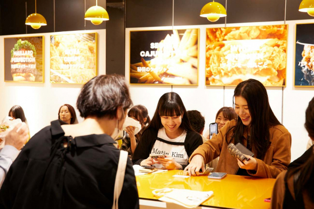 맘스터치가 지난 20일 문을 연 도쿄 팝업스토어에 일본 소비자들이 방문해 QR코드로 주문을 하고 있다. 맘스터치 제공