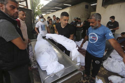 팔레스타인 사람들이 25일 이스라엘의 공습으로 사망한 가족의 시신을 옮기고 있다.  라파 AP 연합뉴스