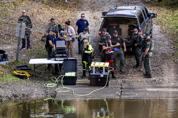 미국 메인주 사법당국 요원들이 이틀 전 총기 난사 사건이 벌어져 18명이 숨지고 13명이 다친 루이스턴에서 조금 떨어진 리스본의 앤드루스코긴강에서 27일(현지시간) 수중 로봇을 투입할 준비를 하고 있다. 리스본 EPA 연합뉴스