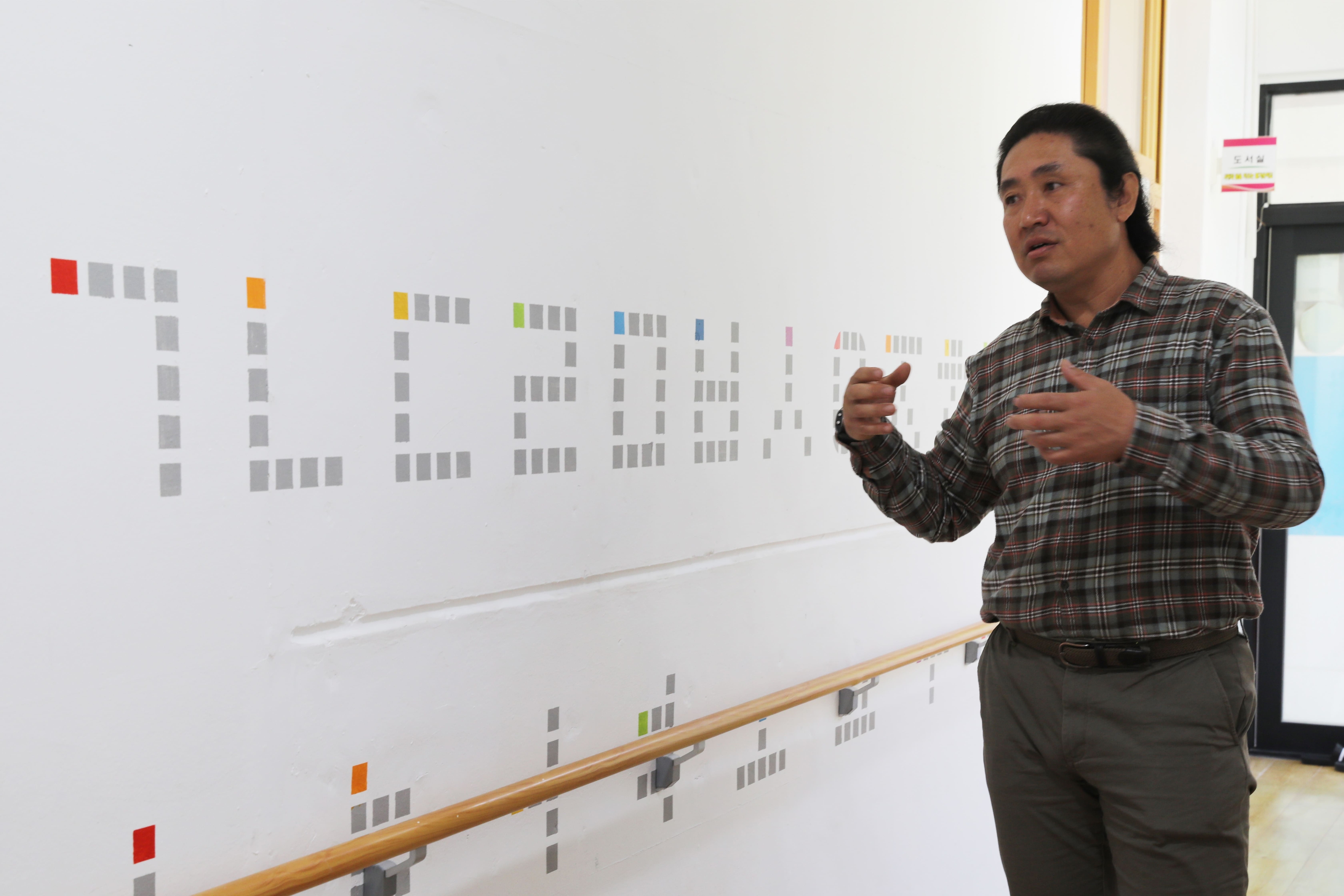 강원 양양시 상평초등학교 공수천분교에서 김재식 씨가 자신의 도색 봉사 작품을 설명하고 있다. KT 희망나눔재단 제공