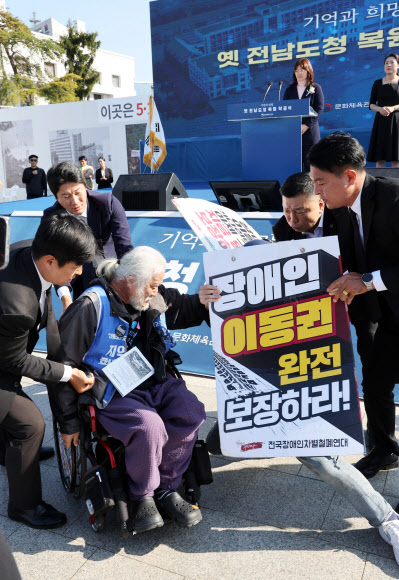 30일 오후 광주 동구 금남로 옛 전남도청에서 열린 ‘옛 전남도청 복원사업 착공식’에서 박경석 전국장애인차별철폐연대 상임공동대표 등이 이동권 확보를 주장하며 피켓 시위를 하고 있다. 2023.10.30 연합뉴스