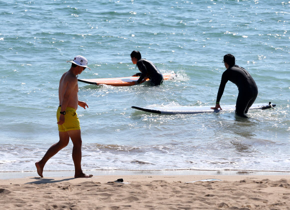 늦더위가 기승을 부리고 있는 3일 부산 해운대구 송정해수욕장에서 한 시민이 상의를 탈의한 채 산책하고 있다. 2023.11.3 연합뉴스