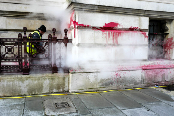 한 일꾼이 7일(현지시간) 런던의 영국 외교부 건물 벽에 팔레스타인 지지 시위대가 페인트를 던져 붉게 얼룩진 것을 닦아내고 있다. 런던 AP 연합뉴스