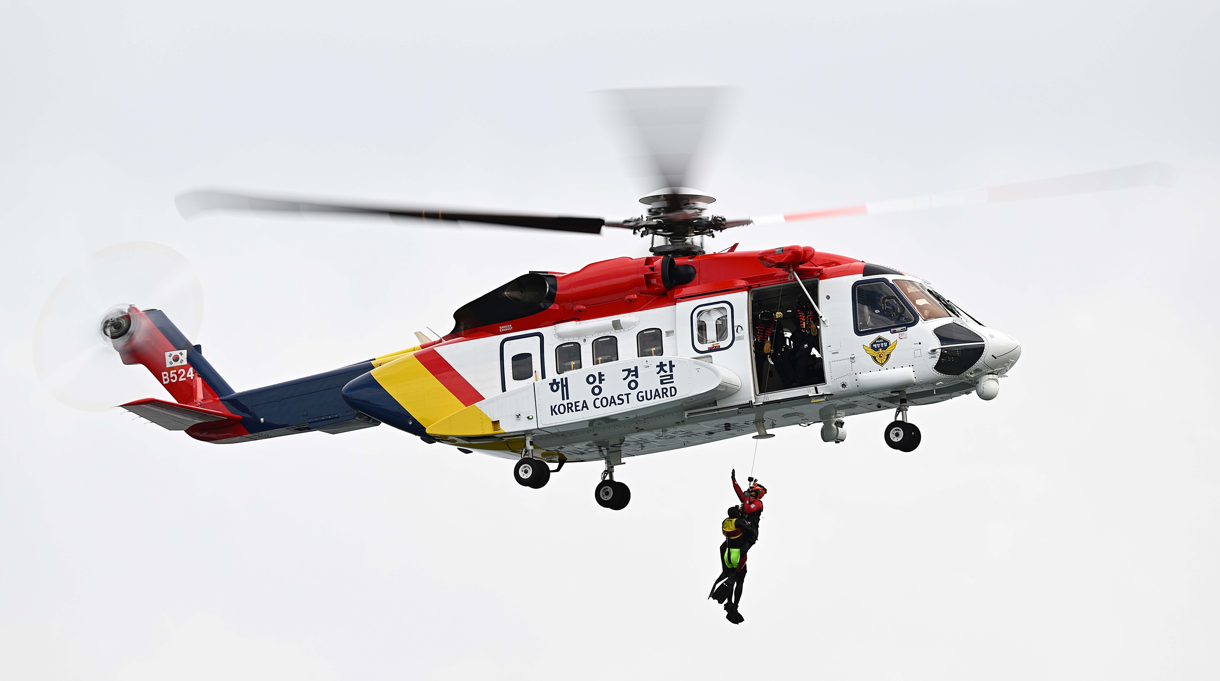 해경의 헬기 S-92호에서 줄을 타고 내려온 대원이 전복된 영덕호에서 탈출해 표류 중이던 선원을 구조하고 있다.