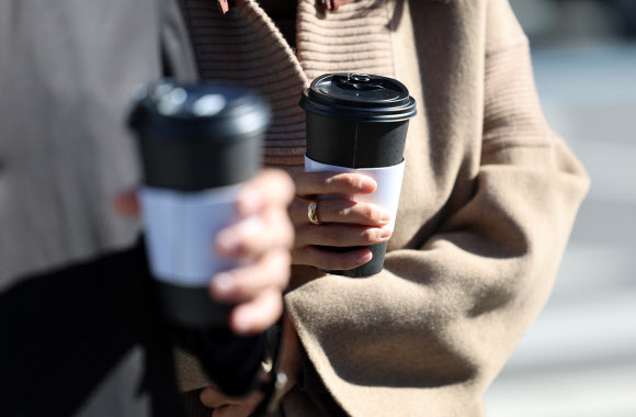 비가 그치며 서울 최저기온이 1도까지 떨어진 10일 서울 종로구 광화문광장에서 시민들이 따듯한 커피를 들고 걷고 있다. 2023.11.10 연합뉴스