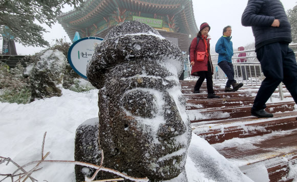 올 가을 들어 가장 추운 날씨를 보인 13일 오전 제주 한라산 1100고지 습지 전시관을 찾은 관광객들이 눈쌓인 탐방로를 걸어가고 있다. 기상청에 따르면 이날 한라산 윗세오름 일최저기온은 영하 5.4도를 기록했다. 2023.11.13 뉴시스