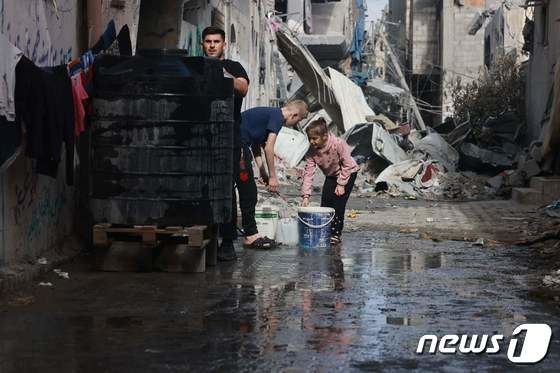 14일(현지시간) 폭우가 내린 가자지구 부레이즈 난민촌의 어린이들이 고인 물을 퍼내고 있다. 부레이즈 난민촌 AFP 뉴스1
