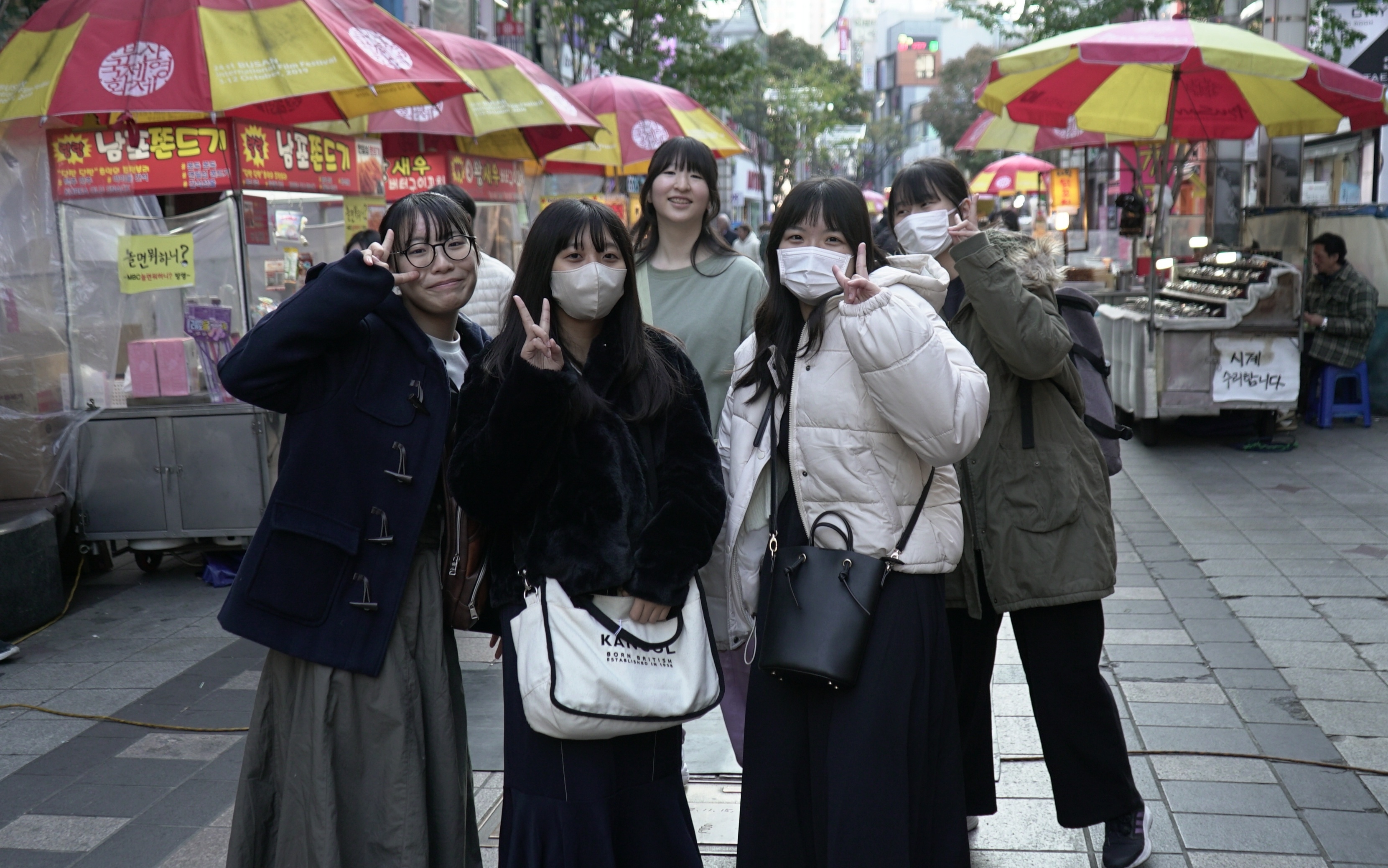 부산 BIFF광장의 먹자골목을 체험하던 오미쿄다이샤고 학생들이 기념사진을 찍고 있다. 한국관광공사 제공.
