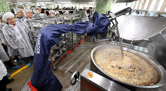 조희연 서울시교육감과 손웅희 한국로봇산업진흥원장이 22일 오전 서울 성북구 숭곡중학교 급식실에서 전국 최초로 도입된 급식 로봇을 살펴보고 있다. 급식실 노동자가 발암물질로 인해 폐 건강이 악화한다는 지적에 도입된 급식 로봇은 국과 탕, 볶음, 유탕 등 온도가 높고 위험했던 조리 업무를 사람을 대신해서 한다. 2023.11.22. 공동취재·연합뉴스