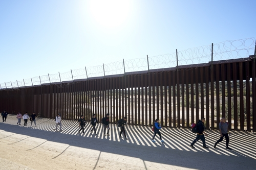 미국으로 이주를 희망하는 중국인들이 24일 미국 캘리포니아 하쿰바 근처의 멕시코 국경 장벽을 따라 걷고 있다. 하쿰바  AP 연합뉴스