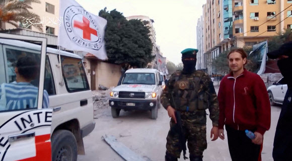 러시아와 이스라엘 이중 국적의 로니 크리보이(25)가 26일(현지시간) 팔레스타인 무장정파 하마스 대원들에 의해 가자지구 모처에서 국제적십자사(ICRC)에 인계되고 있다. 하마스 군사조직 동영상 캡처 로이터 연합뉴스