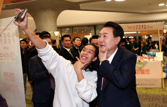 윤석열 대통령이 7일 오후 서울 중구 동대문디자인플라자(DDP)에서 열린 2023년 눈꽃 동행축제 현장을 찾아 5남매를 둔 엄마가 대표인 카카오패밀리 부스에서 대표의 아들과 셀카를 함께 찍고 있다. 2023.12.7  연합뉴스