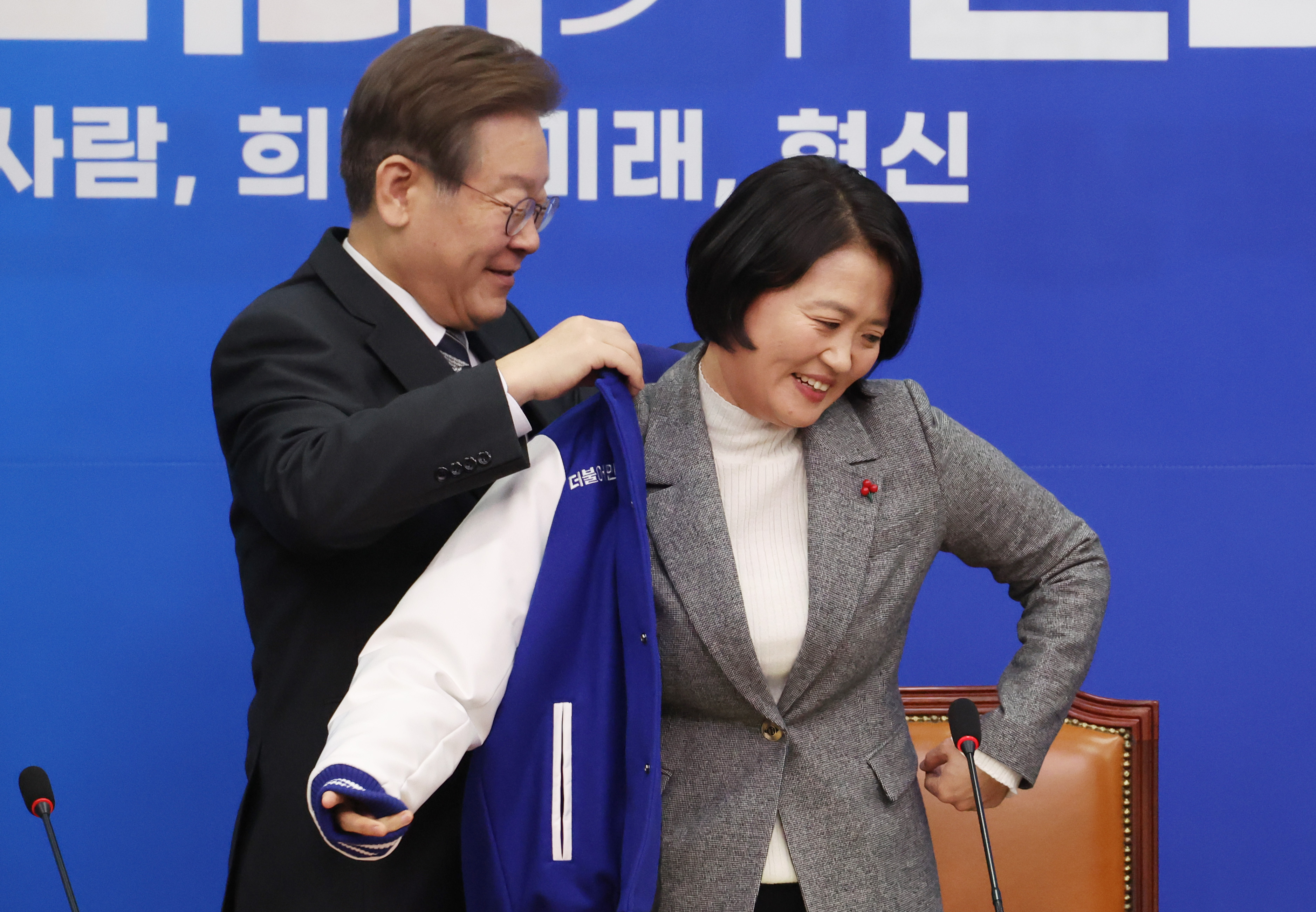 이재명(왼쪽) 더불어민주당 대표가 박지혜 변호사에게 민주당 점퍼를 입혀주고 있다. 2023.12.11 연합뉴스