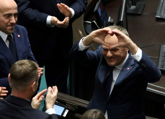 폴란드 야권 연합을 이끌어 8년 만에 총리 지명을 받은 도날트 투스크 시민연합(KO) 대표가 11일(현지시간) 동료 의원들에게 손으로 하트 모양을 만들어 고마움을 표하고 있다. 바르샤바 로이터 연합뉴스