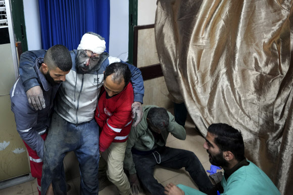 팔레스타인 남성이 19일(현지시간) 이스라엘군의 공습에 머리를 크게 다쳐 가자지구 데이르 알발랄에 있는 병원에 실려오고 있다. 데이르 알발랄 AP 연합뉴스