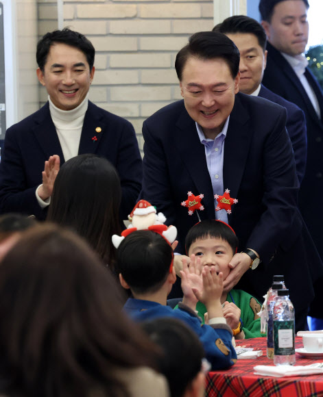 윤석열 대통령이 22일 서울 용산 대통령실 파인그라스에서 열린 ‘히어로즈 패밀리와 함께하는 꿈과 희망의 크리스마스’에 참석한 어린이를 쓰다듬어 주고 있다. 윤 대통령은 이날 행사에 전몰?순직한 군인, 경찰, 소방관 등 제복 입은 영웅들의 자녀와 배우자 등을 초청했다. 2023.12.22   대통령실통신사진기자단