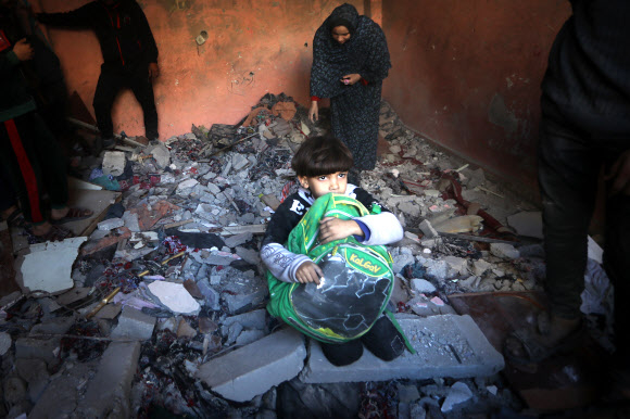 팔레스타인 어린이가 성탄 전야인 24일(현지시간) 가자지구 남부 라파에 있는 자신의 집이 이스라엘군의 공습에 훼손된 잔해 위에 황망히 앉아 있다. 라파 UPI 연합뉴스