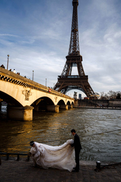 설계자 귀스타브 에펠이 세상을 떠난 지 100년이 되는 27일(현지시간) 프랑스 파리 센 강에서 이 탑을 배경으로 결혼 사진을 촬영하는 커플이 눈에 띈다. 노동조합의 파업으로 이날부터 에펠탑 고층 관광이 중단됐다. 파리 AFP 연합뉴스