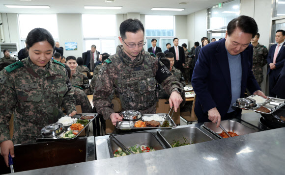 윤석열 대통령이 28일 경기 연천군 군사분계선 전방부대인 육군제5보병사단 5중대 관측소 병영식당에서 장병들과 오찬에 앞서 식판에 음식을 담고 있다. 2023.12.28. 뉴시스