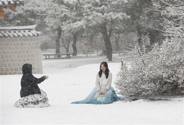 전국 대부분 지역에 눈이 내린 30일 오전 서울 종로구 경복궁을 찾은 관광객이 한복을 곱게 차려입고 사진을 촬영하고 있다. 2023.12.30 뉴스1