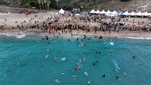 1일 오전 제주 서귀포시 중문해수욕장에서 열린 제25회 서귀포 겨울바다 국제펭귄수영대회에서 참가자들이 바다로 뛰어들고 있다. 2024.1.1 연합뉴스