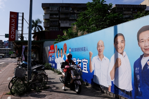 대만 시민이 2일 대선 후보 포스터 앞에서 오토바이를 타고 있다. 타이베이 로이터 연합뉴스