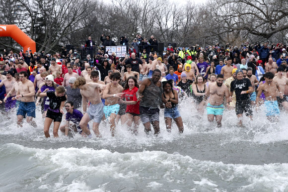 People participate in the annual New Years Day Polar Bear Dip in Oakville, Ont., on Sunday, Jan. 1, 2024. Participants plunge into the frigid waters of Lake Ontario each year to raise money for charity. AP 뉴시스
