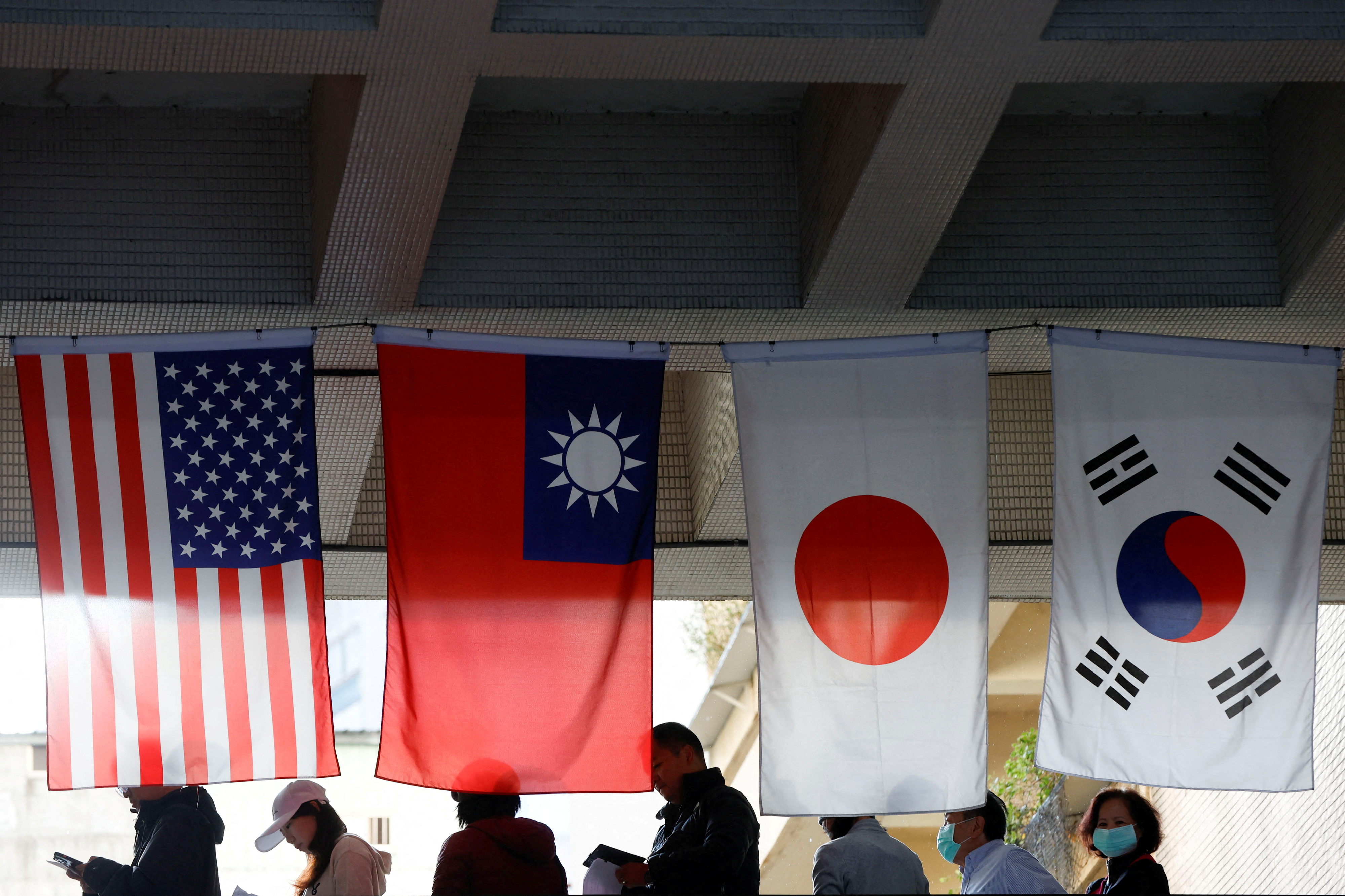 대만 타이베이 시민들이 13일 열린 총통 선거에서 투표하기 위해 미국, 대만, 일본, 한국 등의 국기가 내걸린 곳에서 대기하고 있다. 2024.1.13 타이베이 로이터 연합뉴스