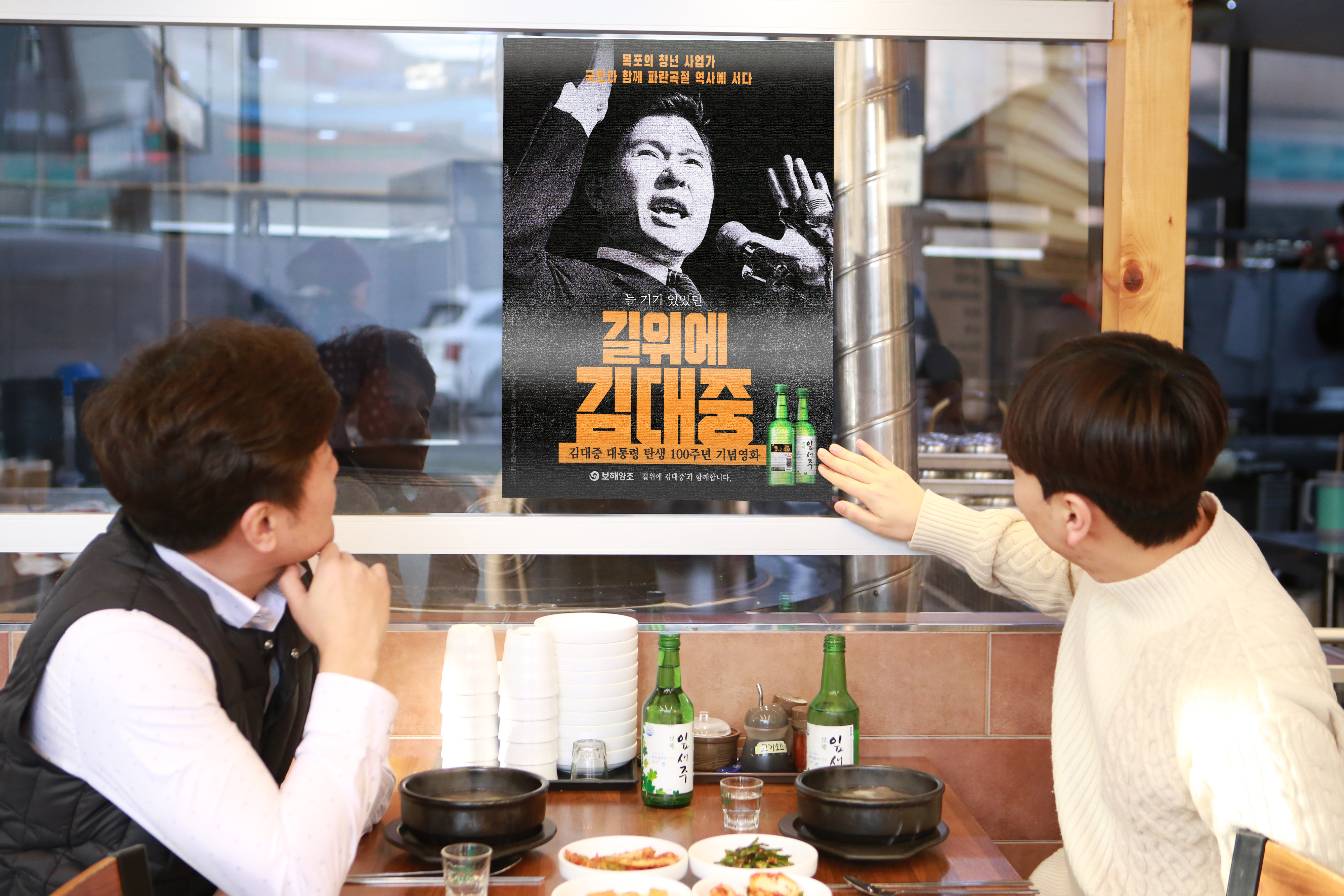 목포 지역 음식점을 방문한 손님들이 보해가 제작한 ‘길위에 김대중’ 홍보 포스터를 보고 있다. 보해양조 제공