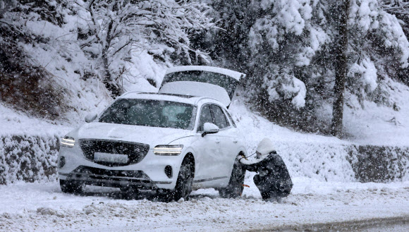 20일 대관령을 비롯한 강원 산간에 대설특보가 내려진 가운데 옛 영동고속도로 대관령 구간에서 한 운전자가 월동장구를 장착하고 있다. 2024.1.20  연합뉴스