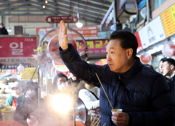 윤석열 대통령이 25일 경기도 의정부시 의정부제일시장을 찾아 어묵을 먹으며 시민들에게 인사하고 있다. 2024.1.25 연합뉴스