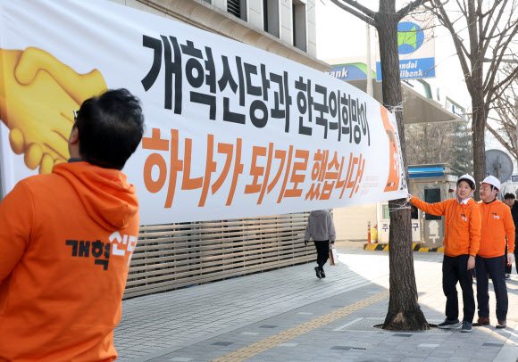 개혁신당 이준석 대표 등이 26일 국회의사당 앞 가로수에 정당 정책 홍보 현수막을 걸고 있다. 2024.1.26 연합뉴스
