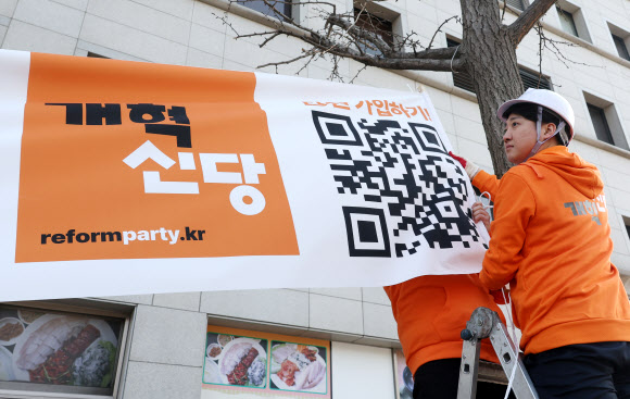 개혁신당 이준석 대표 등이 26일 국회의사당 앞 가로수에 정당 정책 홍보 현수막을 걸고 있다. 2024.1.26 연합뉴스