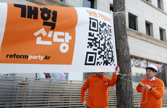 개혁신당 이준석 대표 등이 26일 국회의사당 앞 가로수에 정당 정책 홍보 현수막을 걸고 있다. 2024.1.26 연합뉴스