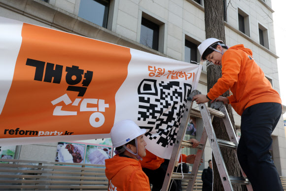 개혁신당 이준석 대표 등이 26일 국회의사당 앞 가로수에 정당 정책 홍보 현수막을 걸고 있다. 2024.1.26 연합뉴스