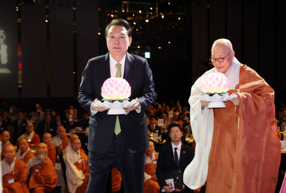 윤석열 대통령이 30일 서울 강남구 그랜드 인터컨티넨탈 서울 파르나스 호텔에서 열린 ‘새해맞이, 나라와 민족을 위한 불교 대축전’에서 한국불교종단협의회 회장 진우 스님과 함께 연등을 공양하고 있다.   2024.1.30  연합뉴스