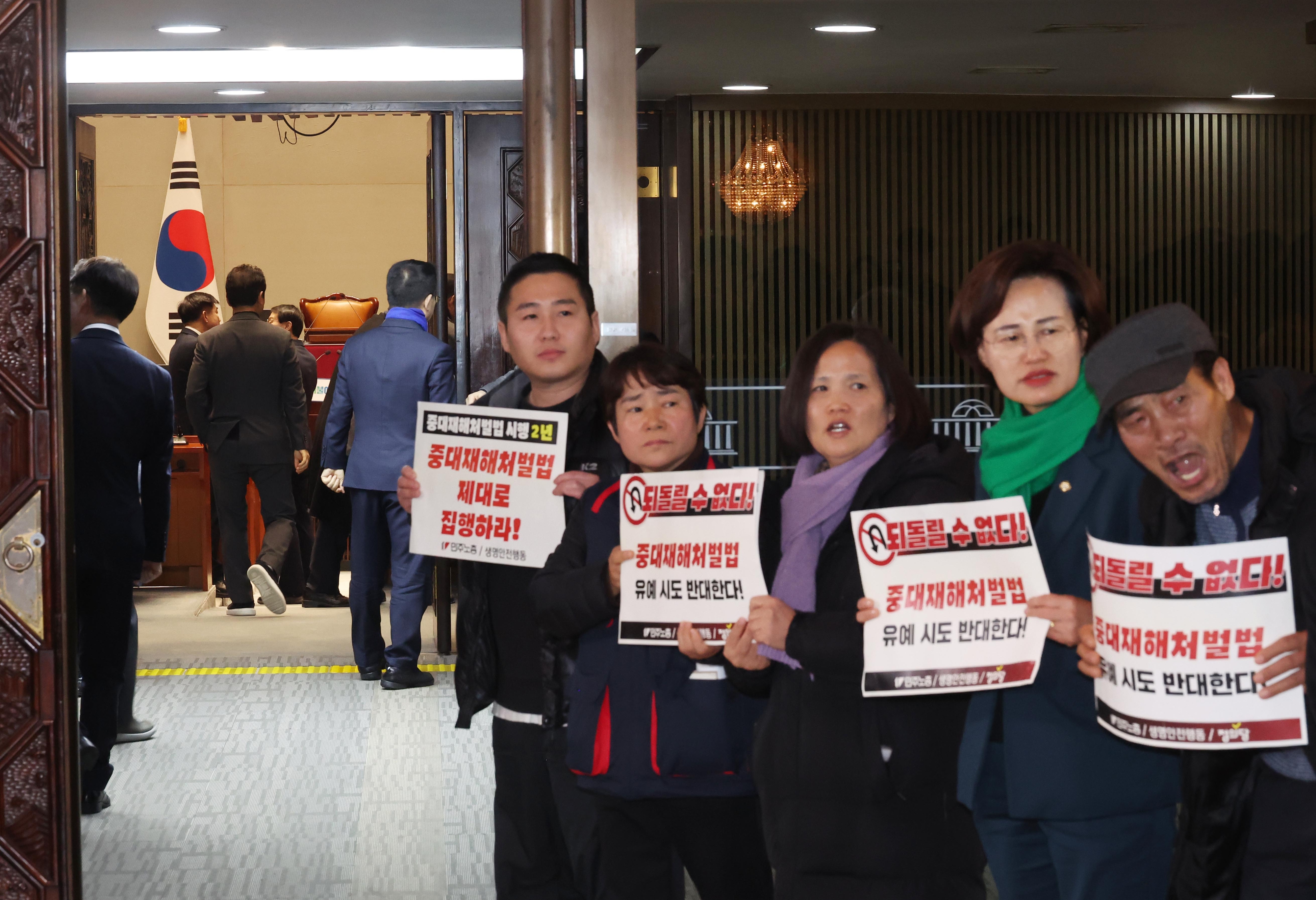 1일 국회에서 열린 더불어민주당 의원총회 앞에서 정의당과 노동계 관계자들이 회의장으로 향하는 의원들을 향해 중대재해처벌법 유예 반대를 외치고 있다. 연합뉴스