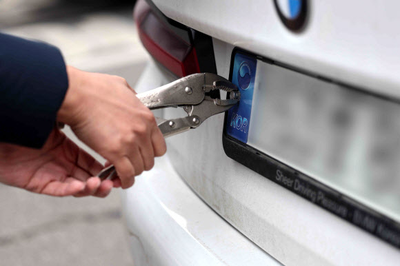 자동차 번호판 봉인 제도 폐지안이 국회 본회의를 통과한 다음날인 2일 오전 서울 송파구청에서 한 시민이 번호판 교체를 위해 봉인을 제거하고 있다. 봉인제도는 자동차 번호판의 위·변조를 막기 위해 번호판을 고정하는 좌측 나사를 스테인리스 캡으로 봉인해야 하는 제도다. 기술발달로 위·변조 방지 및 확인이 쉬워져 불필요하다는 지적이 제기돼 폐지가 추진되고 있다. 2024.2.2  연합뉴스