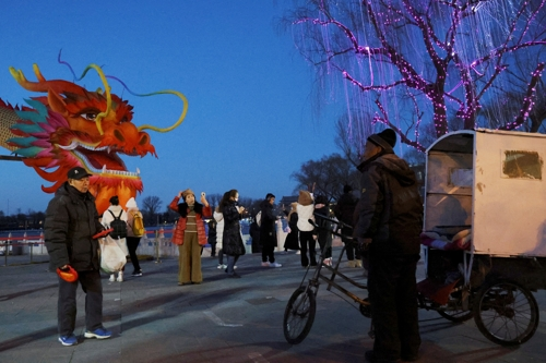 인력거가 음력 설을 앞두고 청룡의 해를 맞아 설치된 용 모양의 조형물 앞에서 사진을 찍는 손님을 기다리고 있다. 베이징 로이터 연합뉴스
