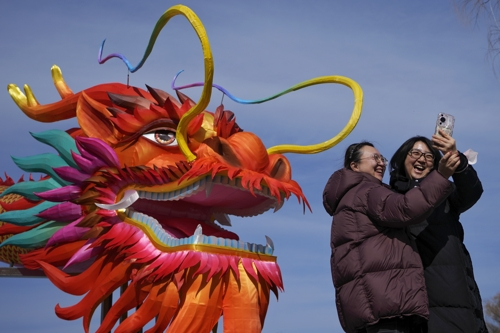 중국 여성들이 청룡의 해를 맞아 얼어붙은 허우하이 호수 근처의 용 모양 등 앞에서 사진을 찍고 있다. 베이징 AP 연합뉴스
